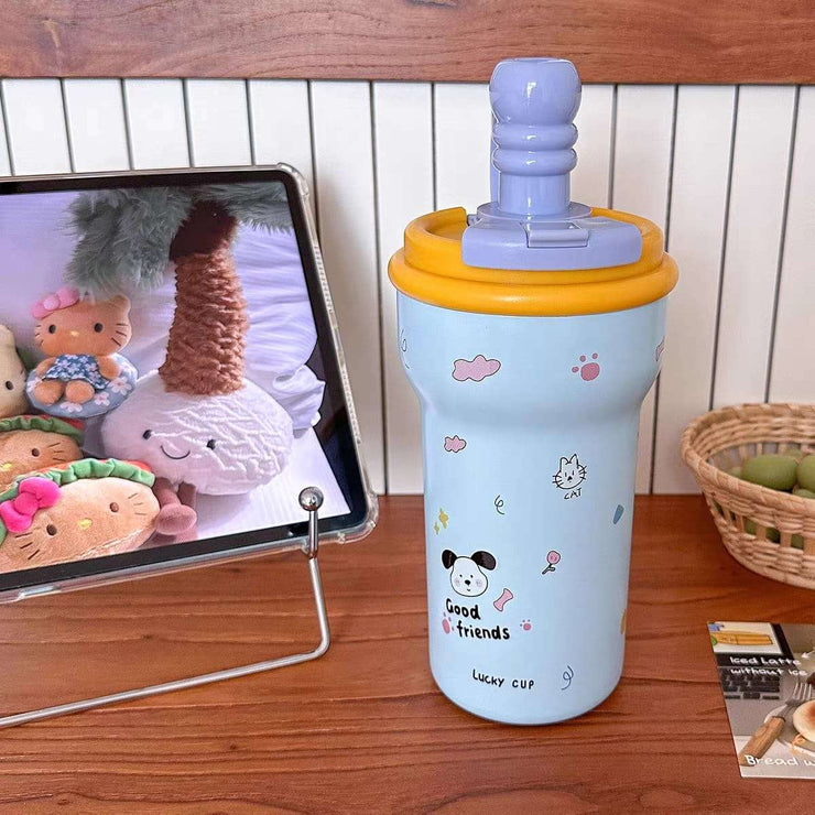 Children's tumbler with cartoon designs on a wooden table next to a tablet displaying cartoon characters.