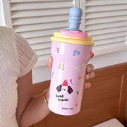 Person holding a pink tumbler with cartoon designs and colorful lid.
