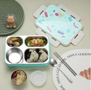 Children's bento box with compartments, utensils, and a decorative plate on a light background