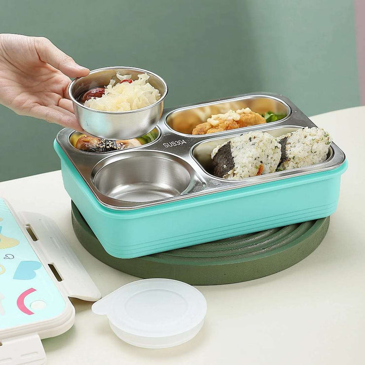 Turquoise and green bento box with compartments filled with food on a light surface.