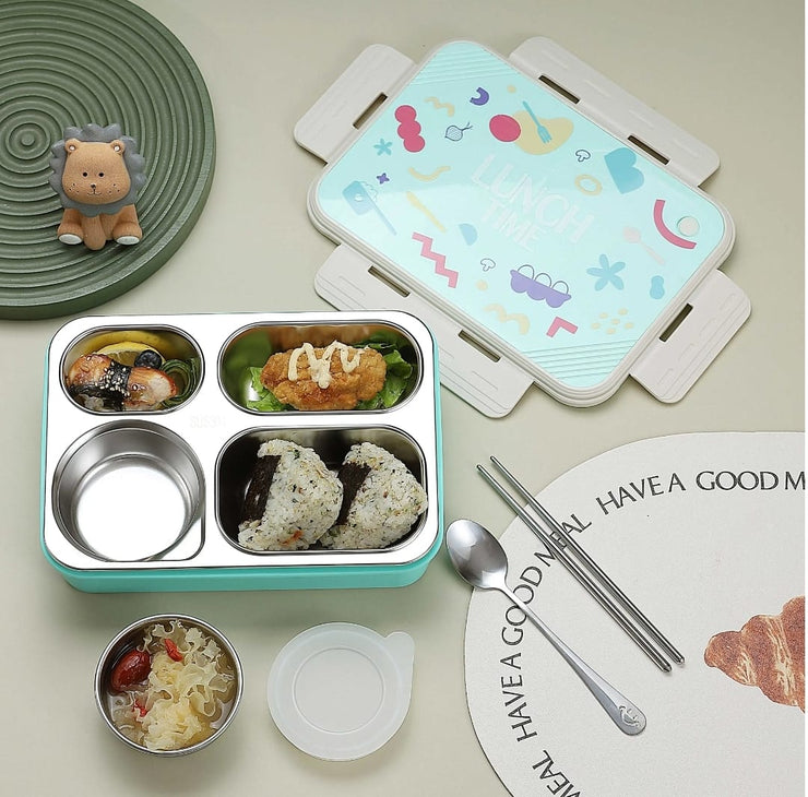 Children's bento box with compartments, utensils, and a decorative plate on a light background