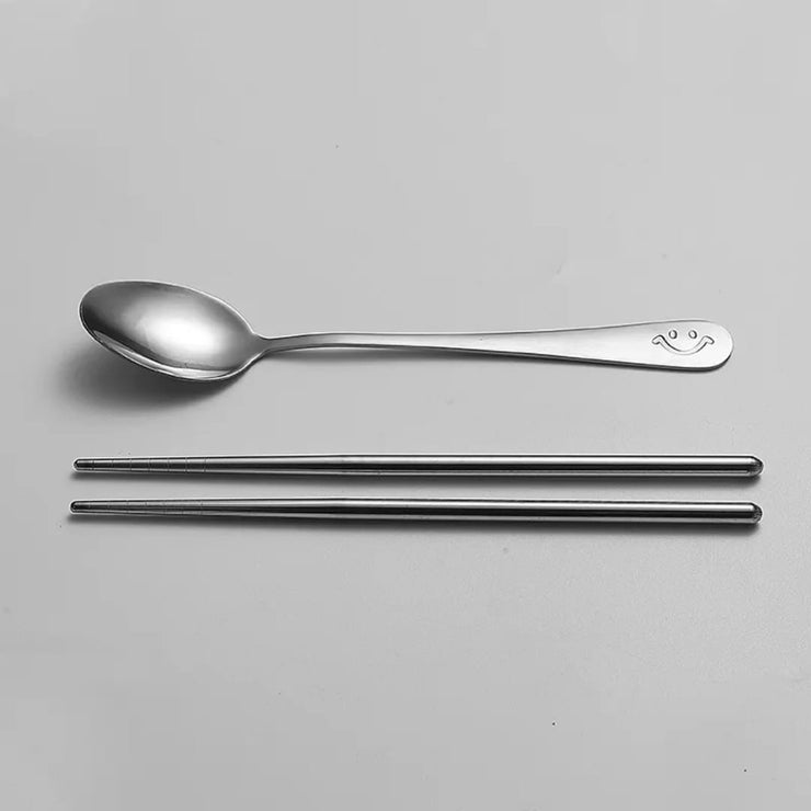 Set of stainless steel spoon and chopsticks on a gray background