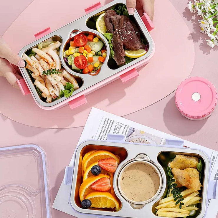 Bento box with compartments of food on a pink surface