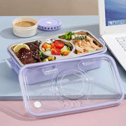 Meal prep container with compartments of food on a desk next to a laptop.