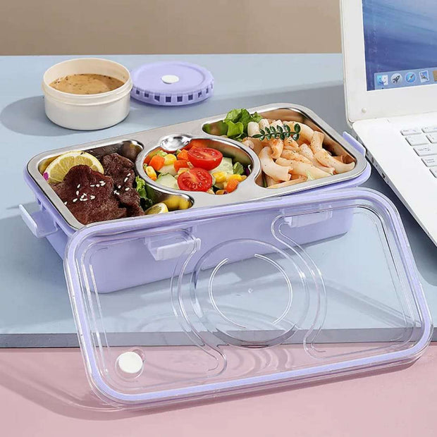 Meal prep container with compartments of food on a desk next to a laptop.