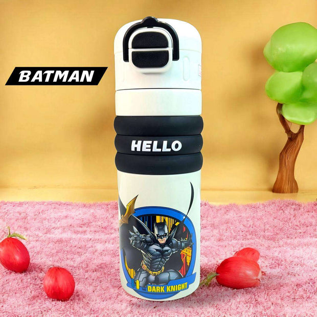 Batman-themed water bottle with 'HELLO' on a pink surface with red flowers and a green tree.