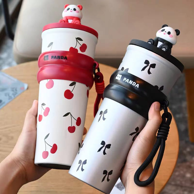 Two panda-themed water bottles held by a person, one with cherry design and red strap, the other with black panda design and black strap.